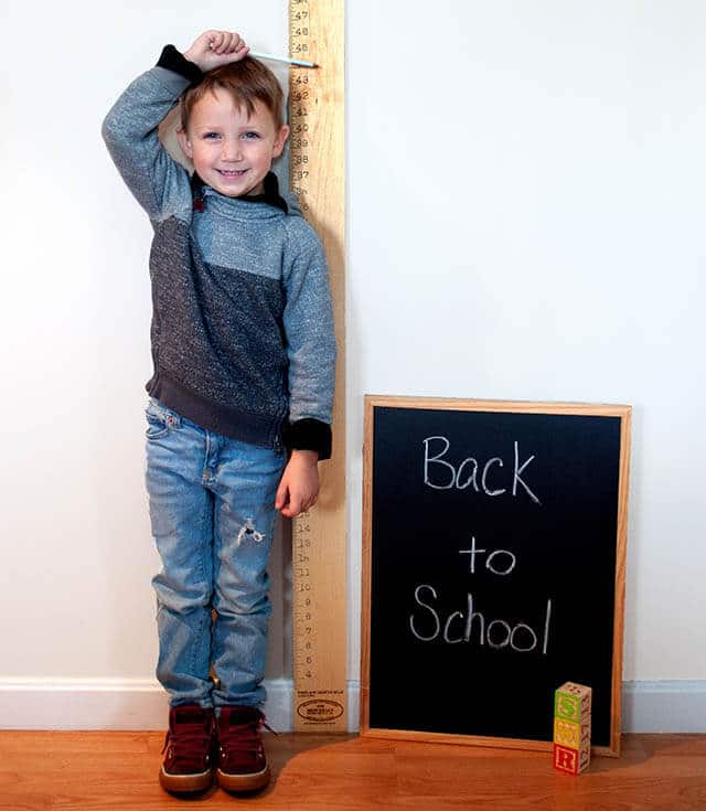 Boy measuring height with growth chart for back to school